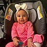 Illiana is registered to the contest to win money with this photo: baby, child, car_seat, pink_clothing, polka_dot, headband, bow, pacifier, smiling, indoors, happy, cute, infant, diaper, sitting, person, face, hand, footwear, cozy