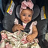 Illiana is registered to the contest to win money with this photo: baby, child, car_seat, pink_bow, blanket, smile, happy, infant, seatbelt, clothing, headwear, portrait, cute, young_child, indoors, sitting, fabric, person, toddler, car_interior