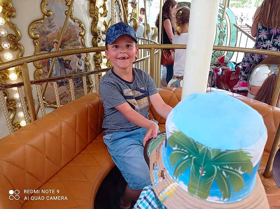 Antoine participe au concours pour gagner de l'argent avec cette photo : amusement_park, amusement_ride, chair, child, event, fashion_accessory, fun, happy, hat, headwear, joy, leisure, person, recreation, shorts, sitting, smile, sun_hat, t_shirt, toddler