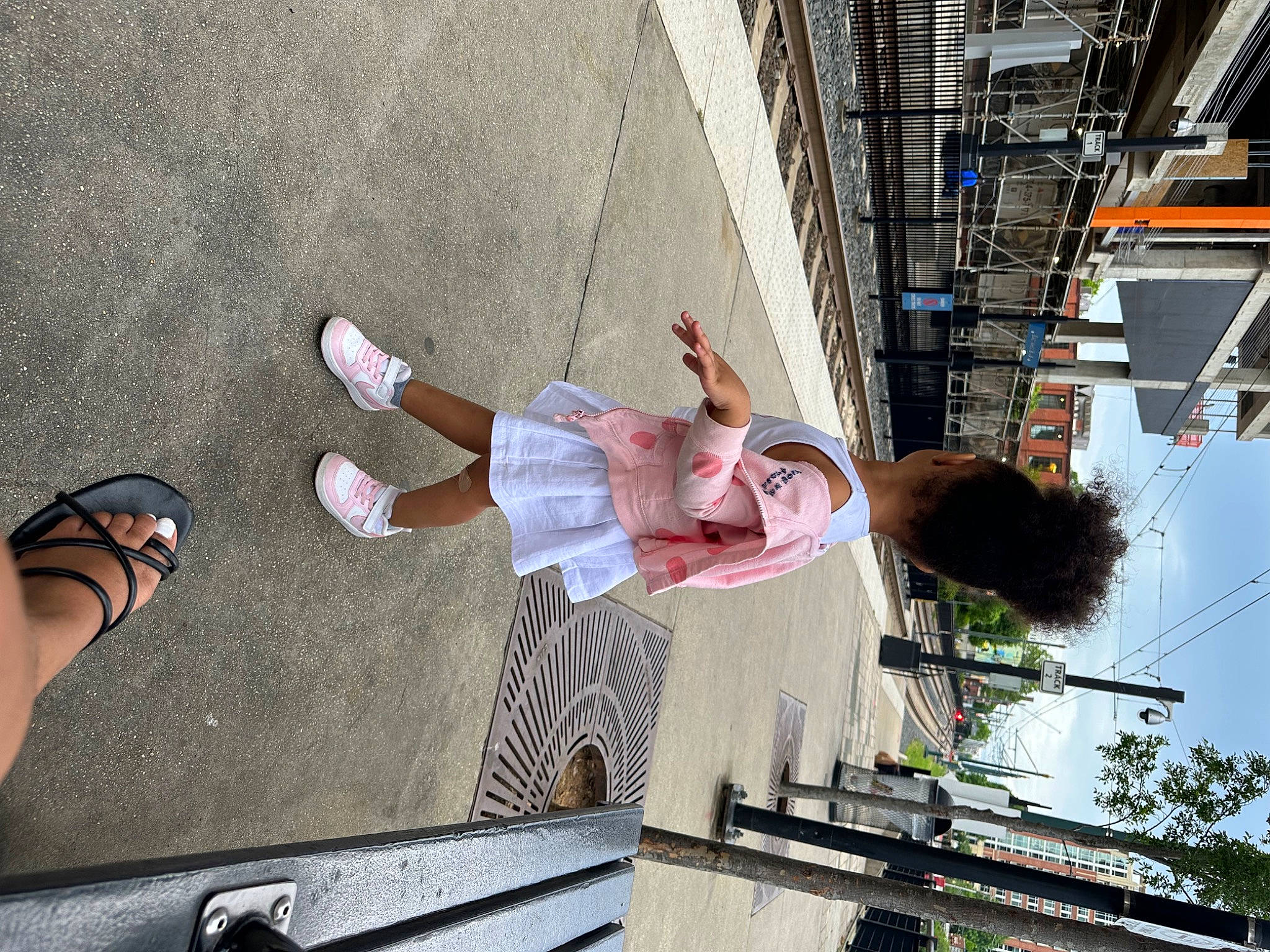 London is registered to the contest to win money with this photo: building, city, facade, foot, fun, human_leg, leisure, pedestrian, person, sandal, sidewalk, sky, snapshot, street, thigh, tree, urban_design, walking_shoe