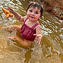 Adelina joined the competition — help win amazing prizes! toddler, child, water, splashing, pink_outfit, toy, water_gun, happy, smiling, outdoor, muddy_water, hair, face, playful, summer, nature, riverbank, sunlight, cute, fun