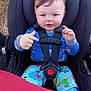 Christopher is registered to the contest to win money with this photo: baby, child, car_seat, blue_eyes, pajamas, colorful_clothing, safety_harness, outdoor, pointing, cute, infant, seat_belt, person, smiling, face, young_child, playful, expression, seat, daylight