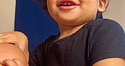 Princeton is registered to the contest to win money with this photo: toddler, child, smile, curly_hair, black_shirt, hand, knee, indoor, curtain, blue, skin, face, person, happy, cute, portrait, young_child, baby, expression, warm_light