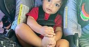 Princeton joined the competition — help win amazing prizes! baby, blanket, car_seat, child, colorful, comfort, cozy, curly_hair, cute, expression, foot, hand, indoors, infant, playful, portrait, red_shirt, seatbelt, toddler, toy