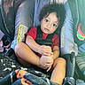 Princeton joined the competition — help win amazing prizes! toddler, child, car_seat, red_shirt, blanket, curly_hair, foot, hand, toy, seatbelt, indoors, portrait, baby, cute, expression, comfort, playful, cozy, colorful, infant