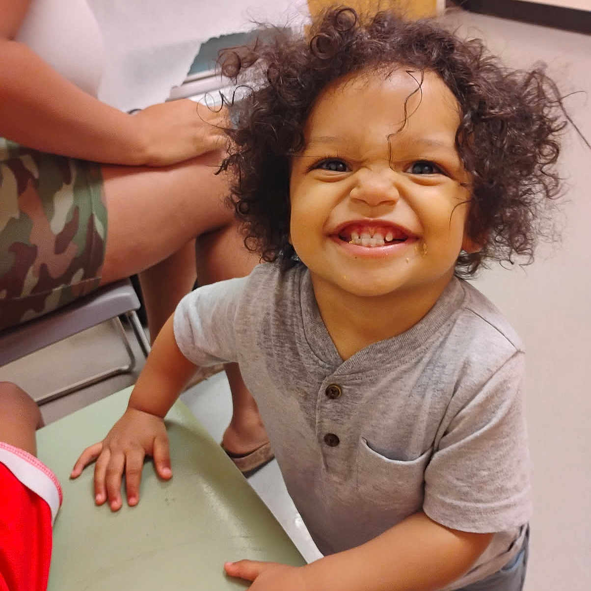 Princeton joined the competition — help win amazing prizes! toddler, child, smile, curly_hair, indoor, table, person, shorts, adult, hand, face, clothing, floor, door, seat, camouflage, happy, expression, playful, footwear