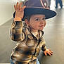 child, toddler, hat, wide_brim_hat, plaid_shirt, jeans, smile, portrait, hand, face, eyes, button, sitting, indoor, bokeh, blurred_background, cute, playful, fashion, warm_tones