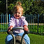 Elsa Stefania is registered to the contest to win money with this photo: child, toddler, playground, outdoor, toy, wooden_toy, smiling, happy, grass, fence, sunlight, greenery, blue_fence, clothing, socks, pants, sweatshirt, play, fun, person