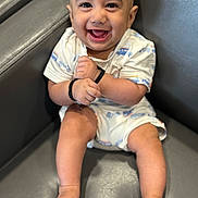 Jalal Ghazi Karrar is registered to the contest to win money with this photo: baby, smiling, happy, infant, child, sitting, couch, clothing, onesie, barefoot, skin, face, hand, foot, bracelet, indoors, portrait, cute, young, leather