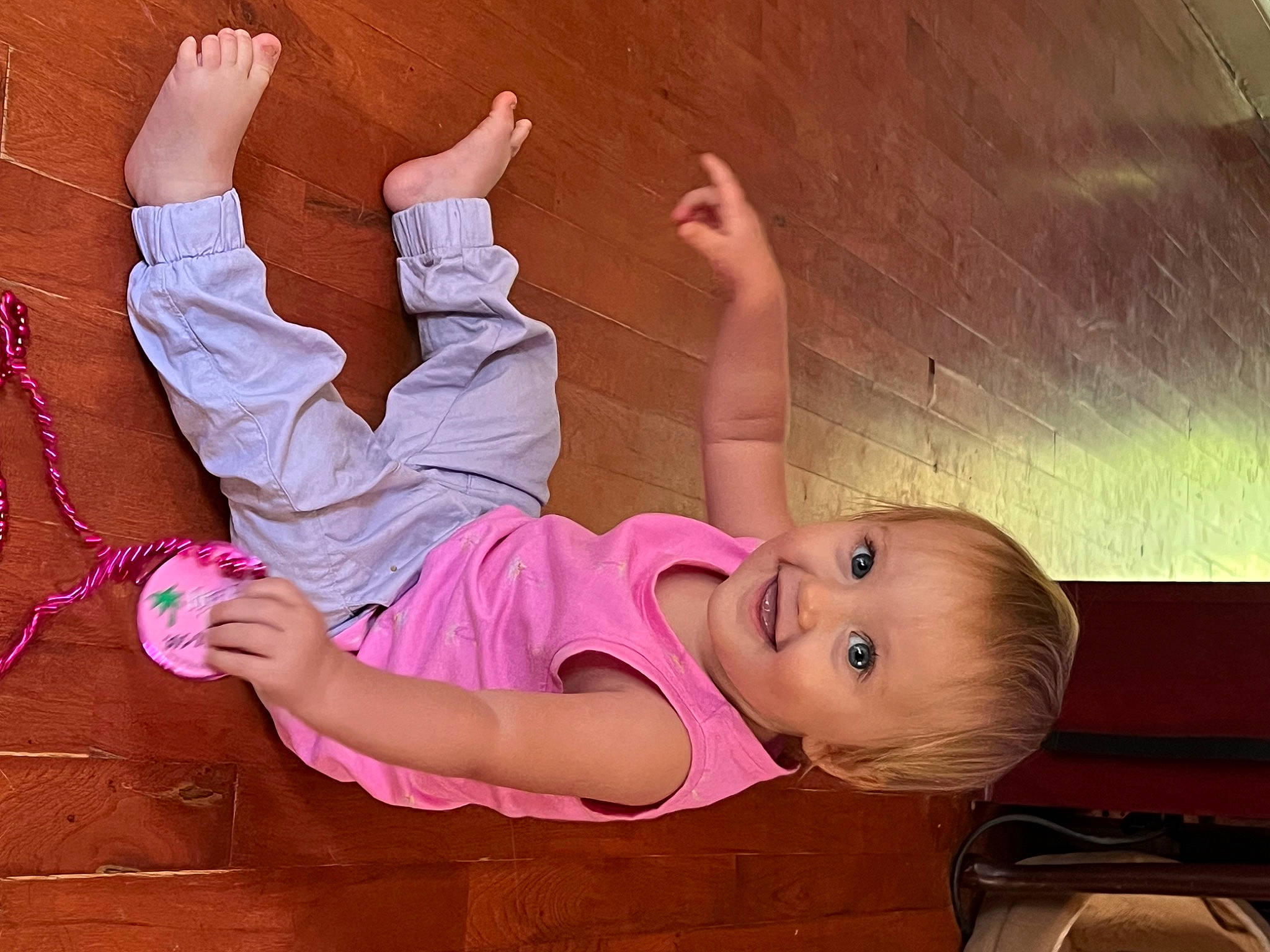 Rosalie is registered to the contest to win money with this photo: arm, baby_toddler_clothing, barefoot, child, foot, footwear, fun, gesture, happy, human_body, human_leg, joy, knee, leg, leisure, person, pink, skin, sock, thigh