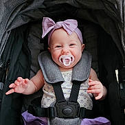 Raven joined the competition — help win amazing prizes! baby, infant, stroller, pacifier, headband, purple_bow, smile, child, happy, cute, clothing, seatbelt, outdoor, person, toddler, fabric, sitting, baby_girl, playful, comfort