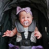 baby, infant, stroller, pacifier, headband, purple_bow, smile, child, happy, cute, clothing, seatbelt, outdoor, person, toddler, fabric, sitting, baby_girl, playful, comfort