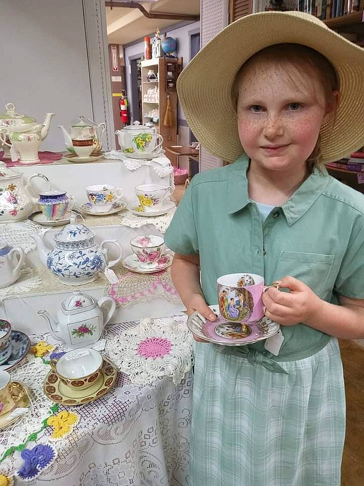 Tatianna is registered to the contest to win money with this photo: coffee_cup, cup, dishware, drinkware, event, hat, joy, linens, market, person, plate, porcelain, public_space, saucer, serveware, smile, sun_hat, table, tablecloth, tableware