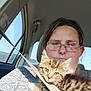 animal, car_interior, casual, cat, closeup, comfort, glasses, human, indoor, kitten, person, pet, portrait, resting, seat, seatbelt, sunlight, tabby_cat, travel, window
