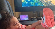 Nova is registered to the contest to win money with this photo: child, toddler, girl, portrait, smiling, happy, sitting, lounging, red_dress, frilly_dress, sneaker, shoe, raised_leg, curly_hair, indoor, living_room, television, cartoon, blanket, couch