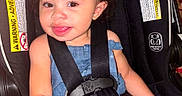 Nova is registered to the contest to win money with this photo: baby, brown_hair, car_seat, child, curly_hair, denim, dress, eyes, face, hair_bow, happy, indoor, photography, portrait, safety_harness, seatbelt, smiling, toddler, tongue, vehicle_equipment