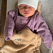 Alicia participe au concours pour gagner de l'argent avec cette photo : baby, sleeping, hat, blanket, purple_clothing, crib, cozy, infant, peaceful, soft_texture, knit_hat, wrapped, resting, indoors, child, newborn, cute, warm, portrait, toddler