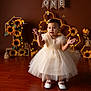 baby, child, dress, birthday, one_year_old, sunflower, bee, decorations, floor, indoor, celebration, portrait, white_shoes, tulle, cute, smiling, happy, girl, event, lighting