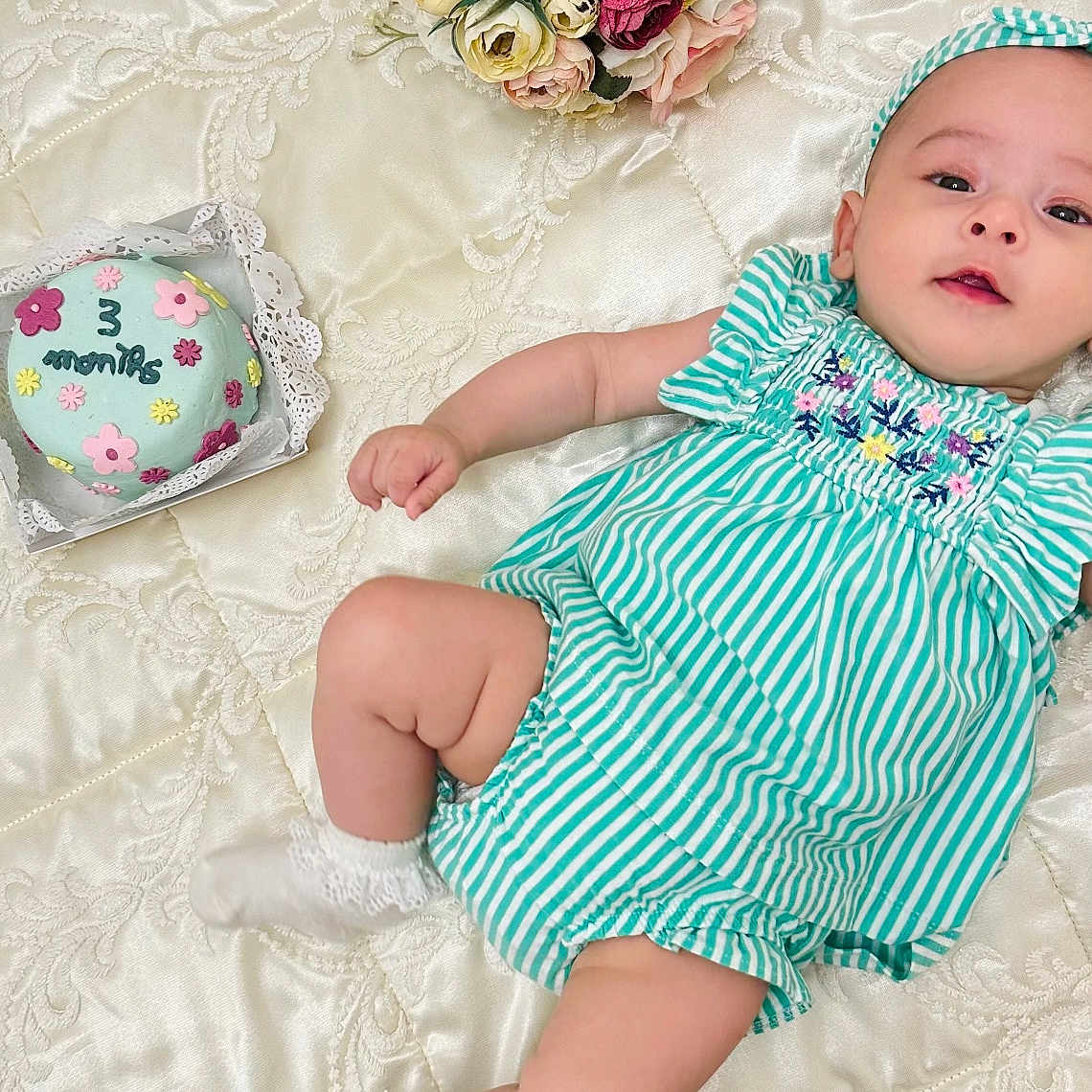 Beya a rejoint le concours — aidez-le/la à gagner de superbes lots ! baby, infant, child, green_striped_outfit, headband, socks, blanket, quilt, cake, floral_bouquet, flowers, celebration, milestone, 3_months, laying_down, cute, portrait, happy, indoor, soft_lighting