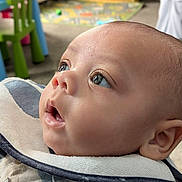 Evin Collin joined the competition — help win amazing prizes! baby, infant, closeup, face, eyes, bib, plaid, clothing, child, curious, indoor, furniture, playmat, soft_light, portrait, young, cute, skin, expression, head