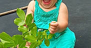 Kyndall joined the competition — help win amazing prizes! toddler, child, smiling, happy, sitting, dress, barefoot, leafy_branch, trampoline, outdoor, greenery, nature, grass, playful, summer, young_child, expression, joy, person, casual