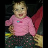 Chevelle Steptoe is registered to the contest to win money with this photo: baby, child, pink_clothing, smiling, person, car_interior, seatbelt, lap, sitting, human_hand, dark_background, screenshot, social_media, screen_interface, long_sleeve, patterned_pants, cute, infant, happy, indoors