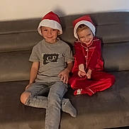 Lyana participe au concours pour gagner de l'argent avec cette photo : casual_clothing, child, children, christmas, couch, face, festive, fun, happy, headwear, holiday, home, indoor, kid, pajamas, relax, santa_hat, sitting, smile, toddler