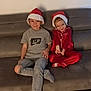 casual_clothing, child, children, christmas, couch, face, festive, fun, happy, headwear, holiday, home, indoor, kid, pajamas, relax, santa_hat, sitting, smile, toddler
