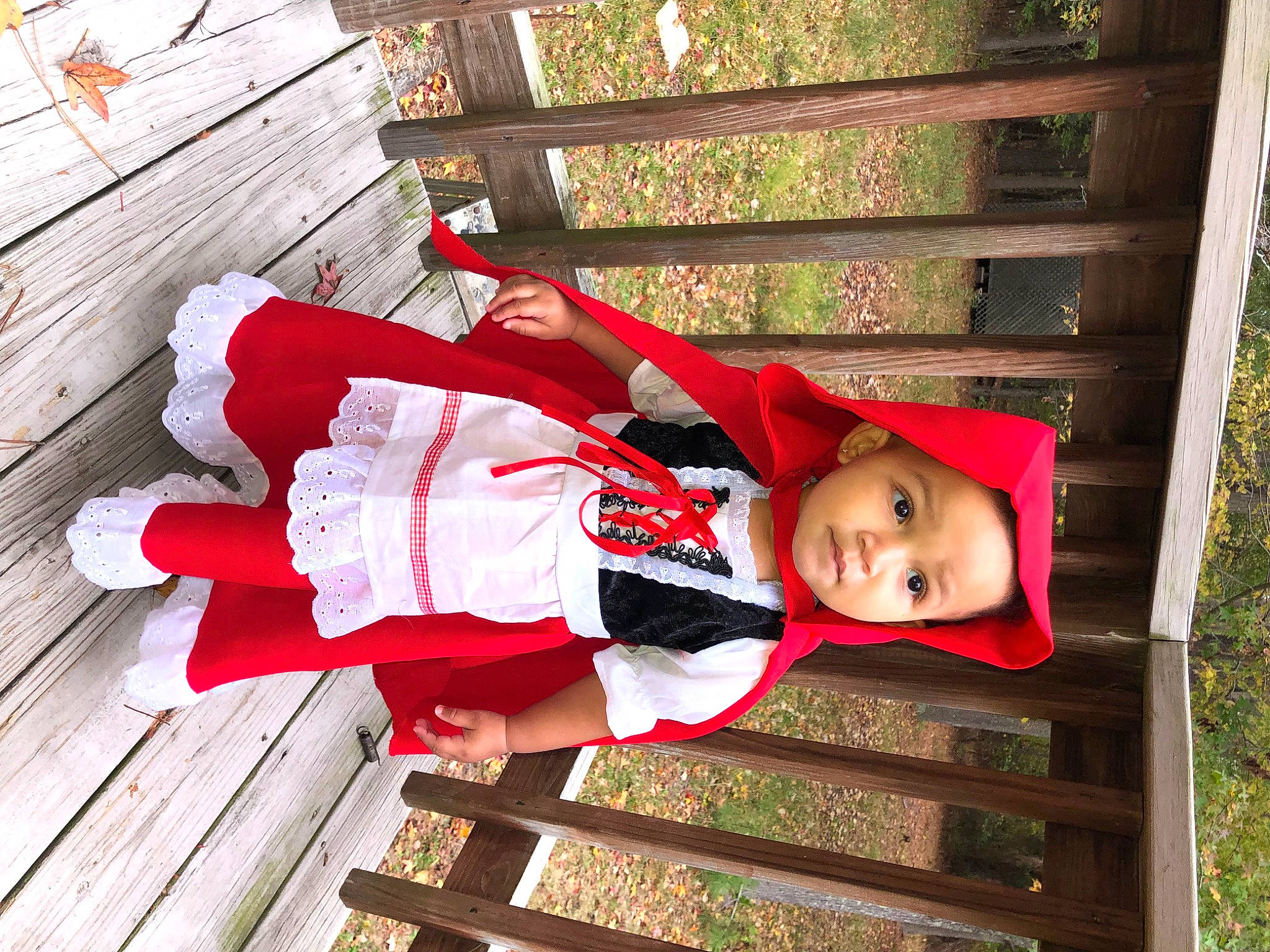 Kya is registered to the contest to win money with this photo: baby_toddler_clothing, carmine, child, fun, grass, happy, hardwood, hat, headwear, leisure, people_in_nature, person, plank, plant, red, smile, thigh, toddler, tree, wood