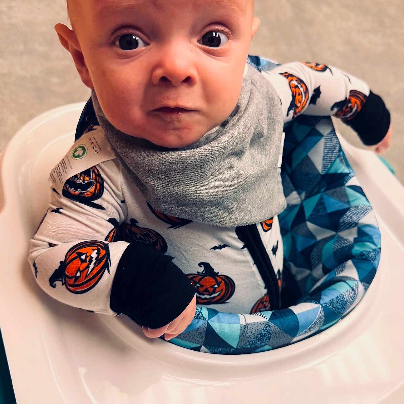 Joshua Corey is registered to the contest to win money with this photo: baby, bib, child, clothing, curious, cute, expression, face, halloween, head, indoor, infant, onesie, patterned, person, pumpkin, sitting, toy, walker, young_child
