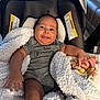 arm, baby, blanket, car_seat, cozy, cute, hand, indoor, infant, leg, living_room, newborn, onesie, person, plush_blanket, seat_canopy, smile, soft_texture, tongue_out, warning_label