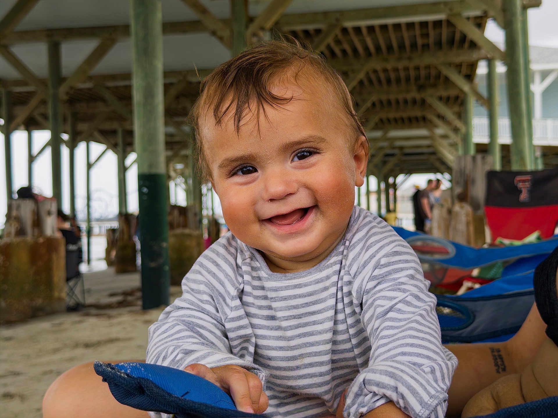 Fox joined the competition — help win amazing prizes! child, toddler, smiling, striped_shirt, beach, sand, pier, wooden_pillars, outdoor, happy, face, person, casual_clothing, daylight, playful, portrait, cute, hands, fun, vacation