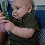 Archie is registered to the contest to win money with this photo: baby, infant, child, toothbrush, green_clothing, curious, bed, pillow, indoor, person, cute, chubby_cheeks, holding, looking, portrait, young, skin, hand, face, expression