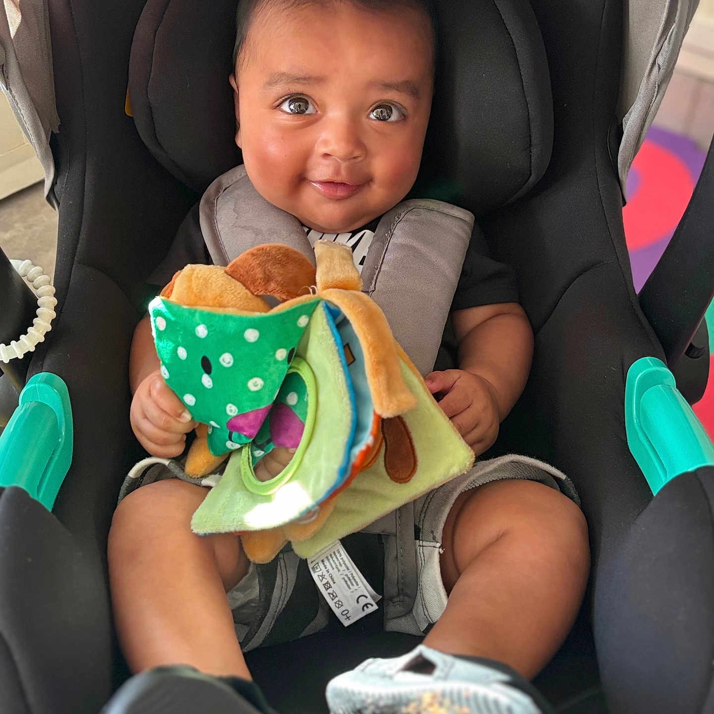 Kayden a rejoint le concours — aidez-le/la à gagner de superbes lots ! baby, car_seat, child, closeup, clothing, cute, footwear, happy, indoor, infant, person, playful, plush, seatbelt, secure, sitting, smiling, soft_toy, toy, young_child