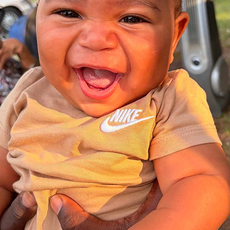 Zyrae is registered to the contest to win money with this photo: arm, baby, background, child, clothing, cute, expression, face, hand, happy, holding, infant, nike, outdoor, person, portrait, skin, smiling, sunlight, tree