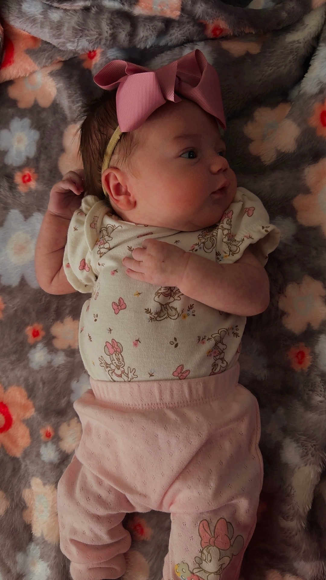 Amelia is registered to the contest to win money with this photo: baby, infant, pink_bow, headband, floral_blanket, cute, sleepwear, pastel_colors, lying_down, newborn, soft_texture, patterned_clothing, mickey_mouse, minnie_mouse, child, portrait, indoors, hand, face, cozy