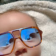 Kolter joined the competition — help win amazing prizes! baby, face, glasses, sunglasses, reflection, blanket, soft_texture, carpet, indoor, close_up, child, infant, cute, serious_expression, head, person, wearing, eyewear, humor, portrait