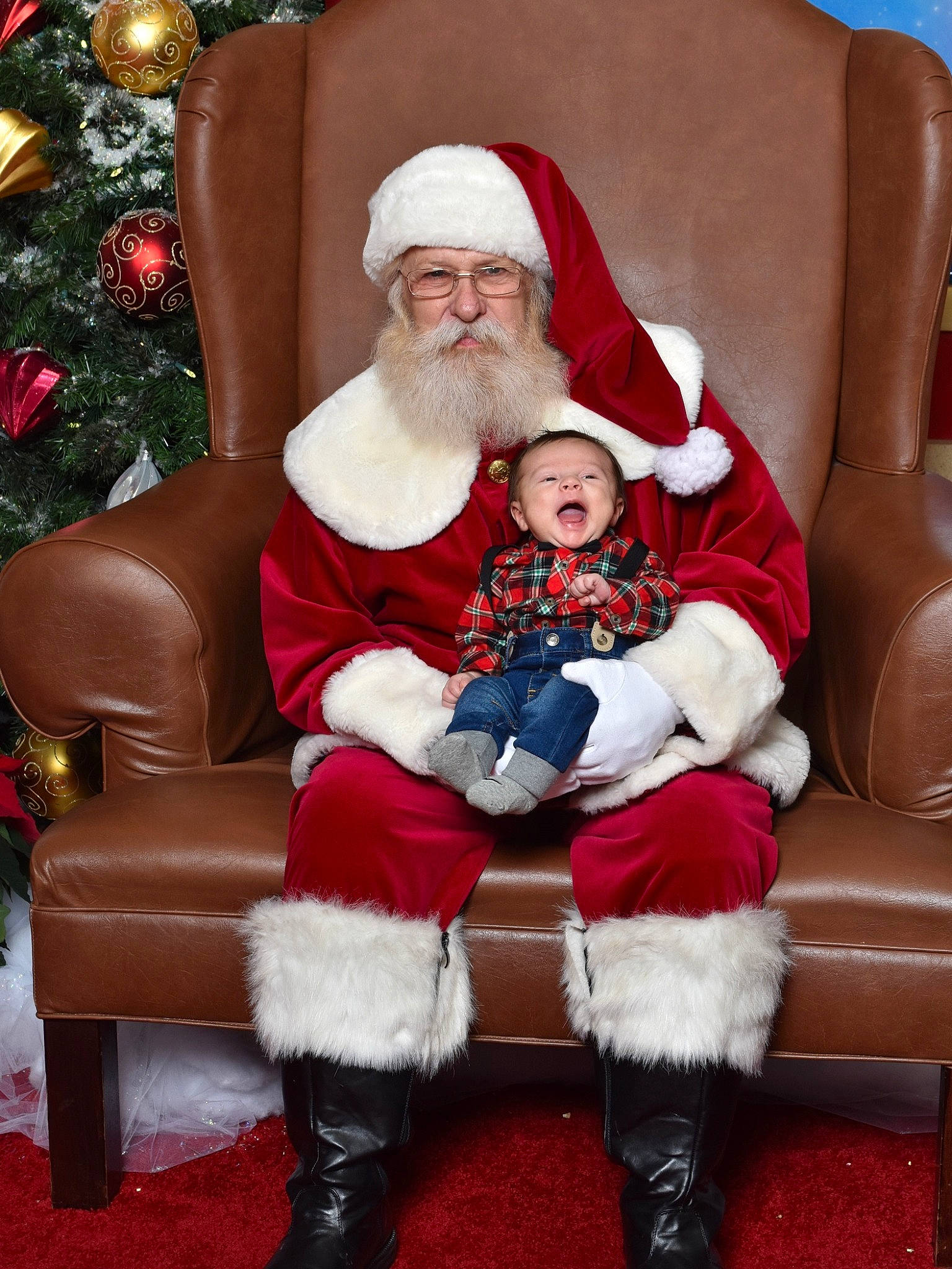 Steve is registered to the contest to win money with this photo: beard, christmas, christmas_tree, comfort, face, facial_expression, facial_hair, happy, hat, head, headwear, human_body, lap, leg, organ, person, red, santa_claus, shoe, smile