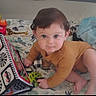 baby, child, onesie, crawling, playmat, toy, patterned, blanket, indoor, curious, blue, mustard, infant, face, person, young_child, cute, smiling, bright_eyes, colorful