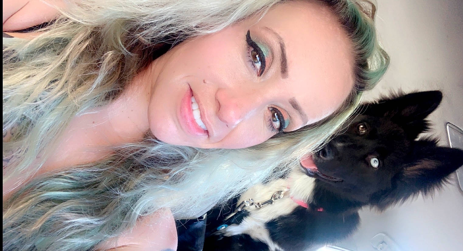 animal, black_dog, car_interior, casual, closeup, companion, dog, eyeliner, face, friendship, happy, heterochromia, indoor, leash, light_hair, long_hair, pet, portrait, smiling, woman
