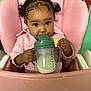 toddler, child, baby, high_chair, pink, sippy_cup, milk, cracker, curly_hair, pigtails, cute, indoors, feeding, small_hand, face, portrait, clothing, jacket, seat, table