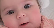 Aurora joined the competition — help win amazing prizes! baby, child, infant, pink_clothing, onesie, face, eyes, pillow, bed, sleepwear, person, portrait, indoor, cute, curious, soft_lighting, young_child, headboard, rosy_cheeks, tousled_hair