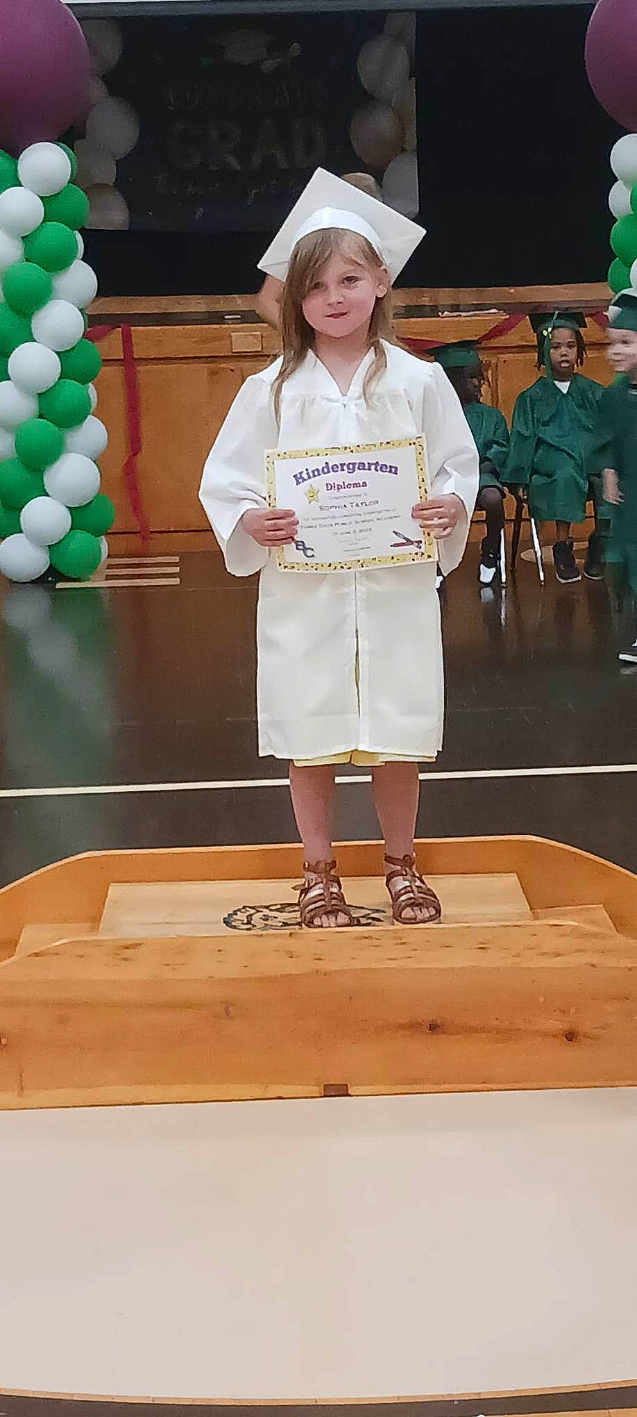 Sophia is registered to the contest to win money with this photo: balloon, baseball_cap, cap, child, competition, competition_event, event, fashion_design, flooring, fun, green, hat, joy, person, recreation, shorts, smile, stage_equipment, t_shirt, uniform