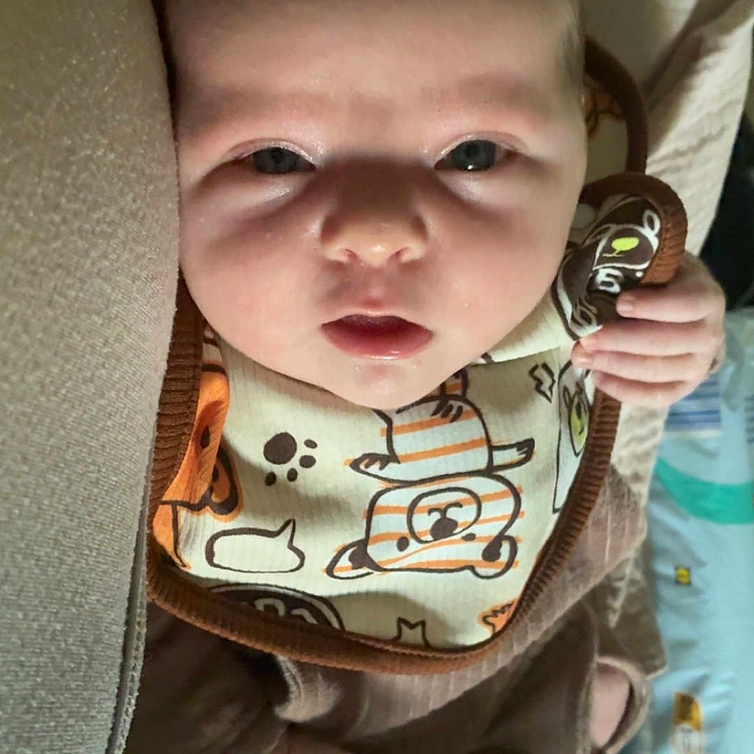 Alliyah a rejoint le concours — aidez-le/la à gagner de superbes lots ! baby, baby_item, bib, brown_outfit, close_up, clothing, curious, cushion, cute, face, hand, indoors, infant, lying_down, newborn, patterned_bib, person, portrait, soft_furniture, soft_lighting