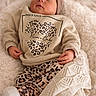 baby, sleeping, infant, blanket, cozy, leopard_print, clothing, headwear, soft_texture, cute, newborn, peaceful, wrapped, warm, portrait, indoor, child, resting, comfort, small