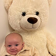 Djino a rejoint le concours — aidez-le/la à gagner de superbes lots ! baby, teddy_bear, smile, plush_toy, soft, cozy, child, cute, indoor, light_background, portrait, happy, infant, clothing, warm_colors, furniture, toy, head, face, cuddle