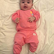 Layla Wright joined the competition — help win amazing prizes! baby, bed, child, comfortable, cozy, cute, expression, face, indoors, infant, lying_down, person, pink_clothing, portrait, sleepwear, small_hands, socks, soft_lighting, white_bed_sheet, young