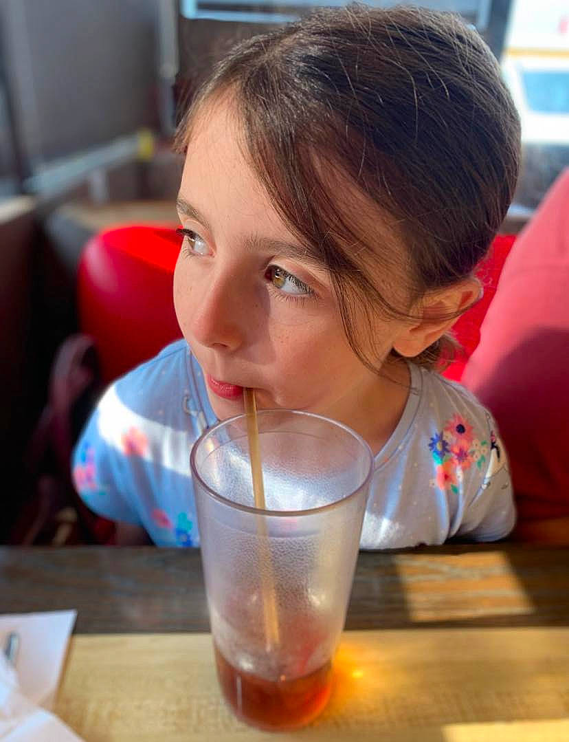 Judith is registered to the contest to win money with this photo: child, distilled_beverage, drink, drinking, drinking_straw, drinkware, flooring, food, fun, glass, ingredient, juice, nose, person, play, sitting, soft_drink, table, tableware, toddler