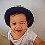 toddler, child, hat, smiling, curly_hair, white_shirt, happy, indoors, portrait, face, cute, baby, person, sitting, looking_up, joyful, casual, skin, eyes, expression
