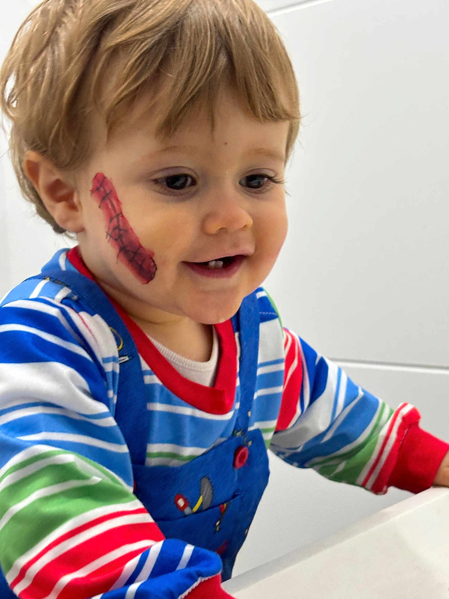 Louca participe au concours pour gagner de l'argent avec cette photo : child, toddler, face_paint, smile, striped_clothing, overalls, cheek_paint, happy, indoor, person, cute, young_child, portrait, colorful_clothes, playful, fun, closeup, baby, expression, light_background